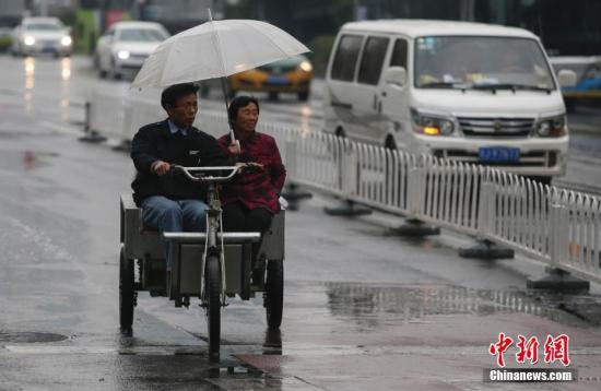 資料圖：民眾在雨中出行。<a target=