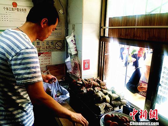 圖為凌君道正在將粽子裝袋進(jìn)行售賣?！「呖档?攝