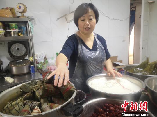 鄭春玲將兩張大粽葉窩成漏斗狀，填上糯米，放上兩粒紅棗，再加一片小粽葉，用棉線纏繞綁好，一個(gè)紅棗粽就成了，用時(shí)僅8秒。　高康迪 攝